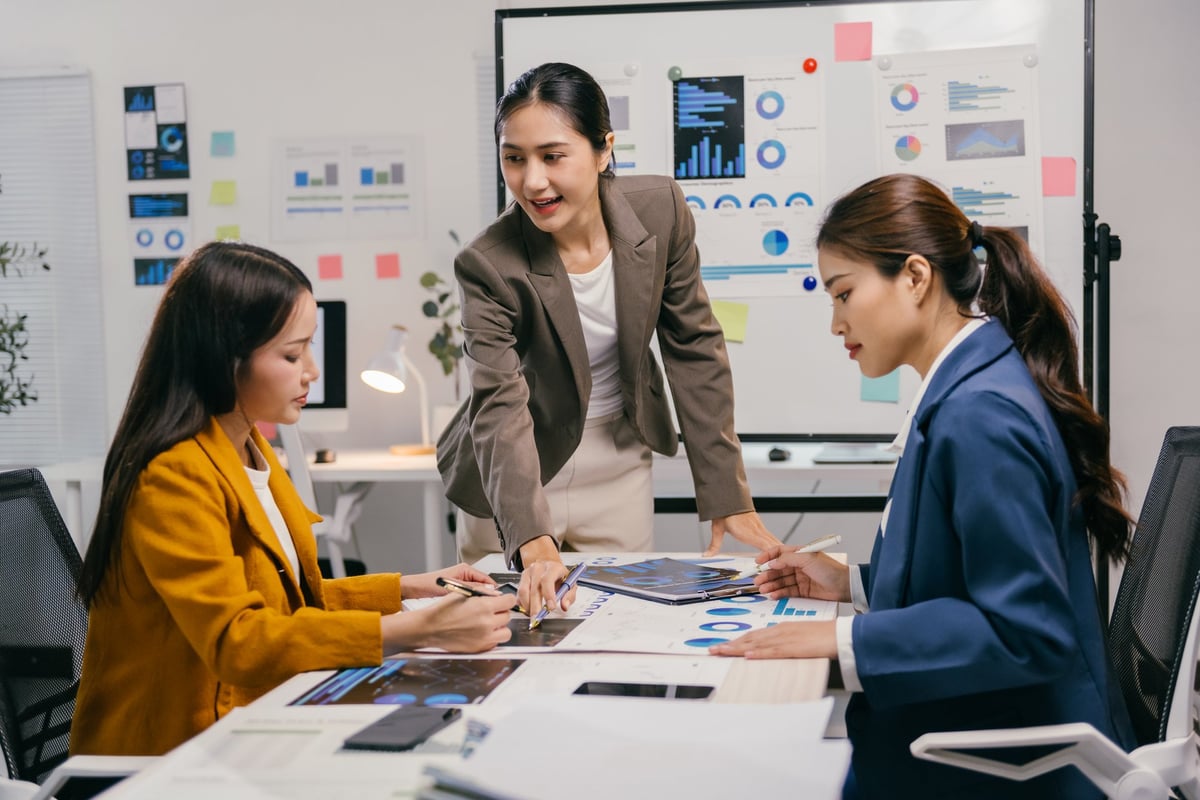 Three professionals collaborating on workforce strategy charts in a modern office