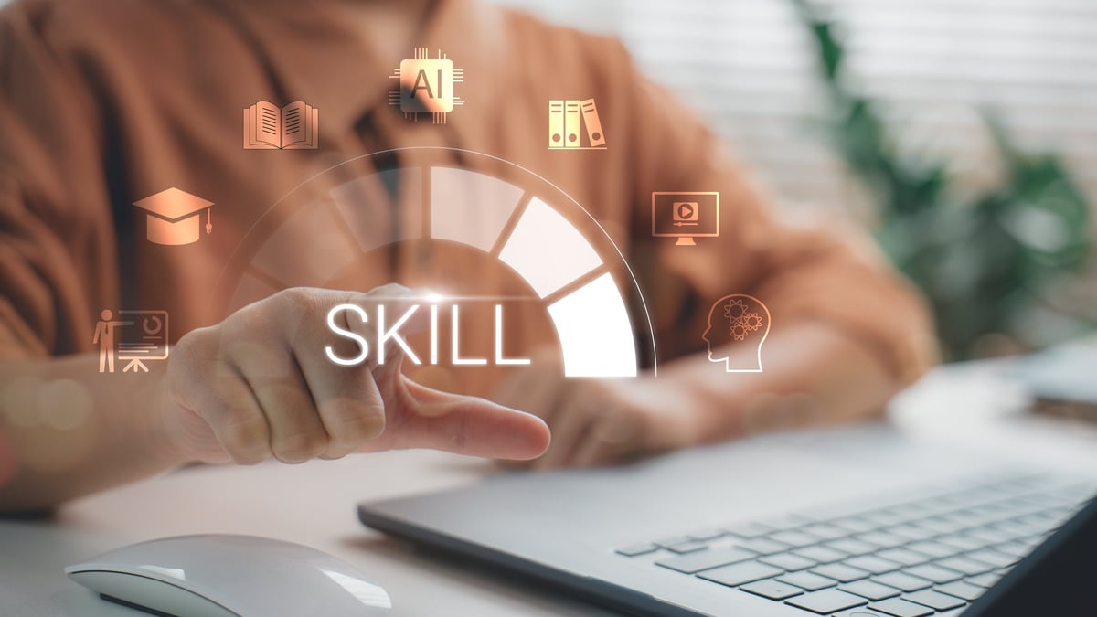A person pointing at a virtual skill development icon on a laptop screen